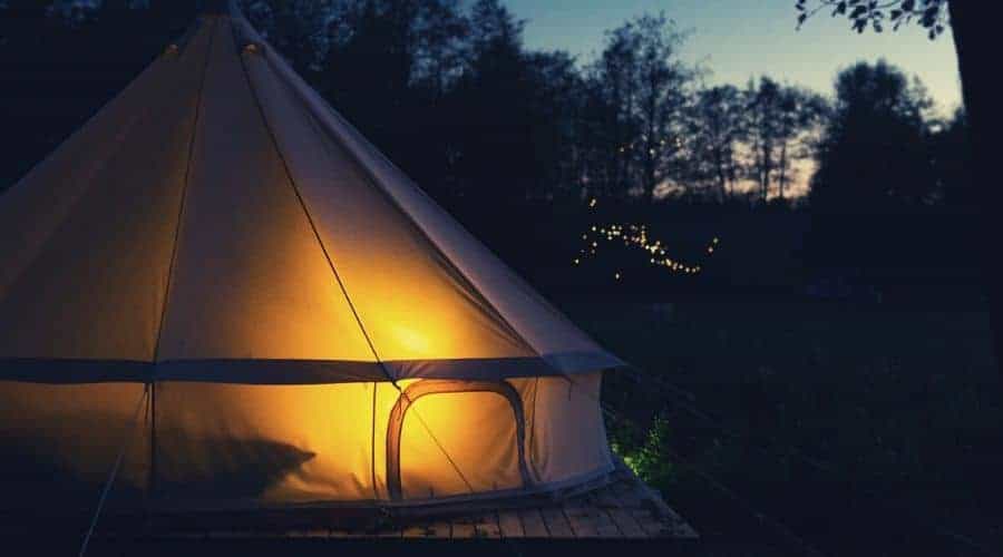 large bell tent in the dark illuminated by lantern