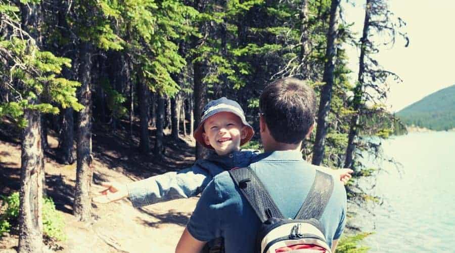 happy boy carried by father on hiking trip