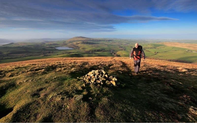 Hiker walking toward rock cairn mound