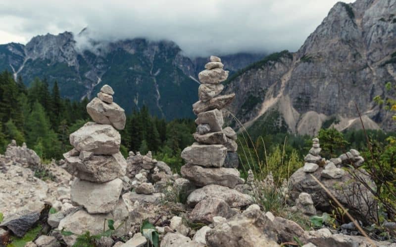 Multiple small rock cairns overlooking a forested mountain area