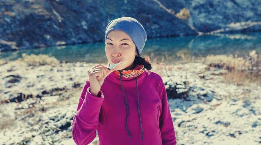 backpacker brushing teeth at mountainside camp