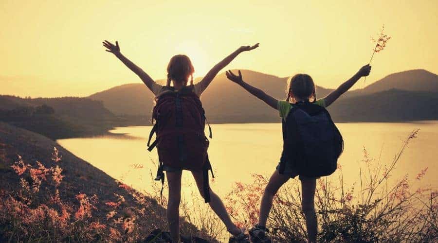 silhoutte of two girls hiking lake intext