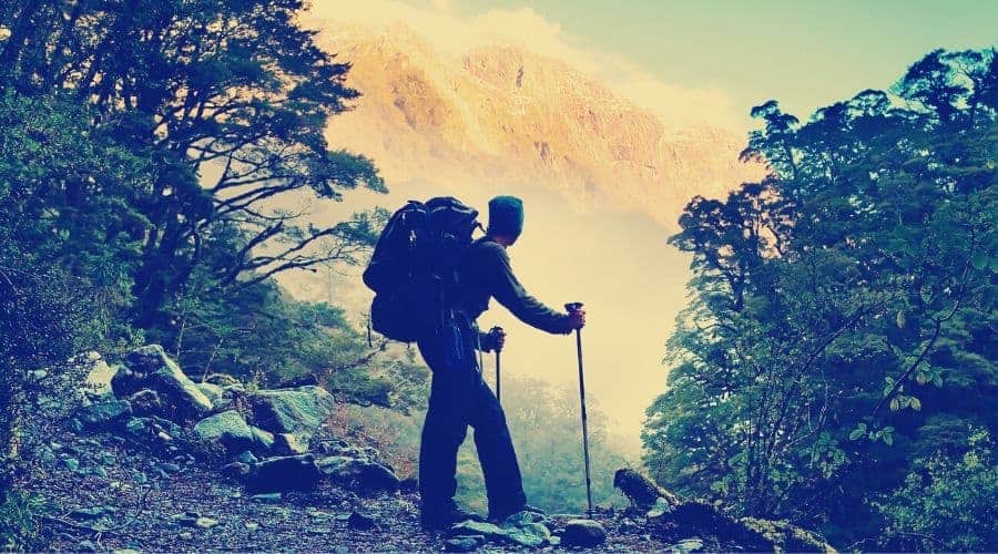 A hiker pauses for a rest at a clearing while ascending into the mountains