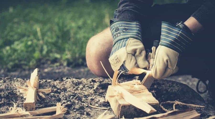 camper preparing kindling for campfire intext