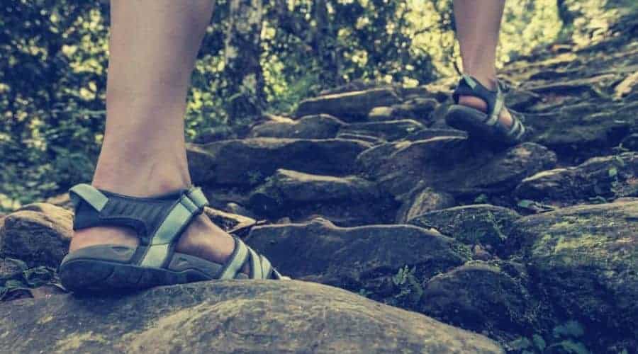 hiker climbing stone trail in hiking sandals intext