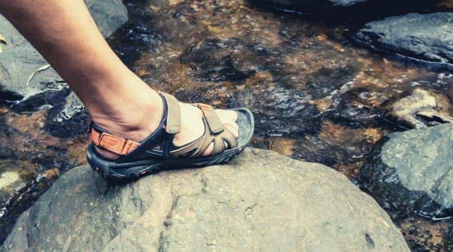 hiker crossing stream in hiking sandals intext