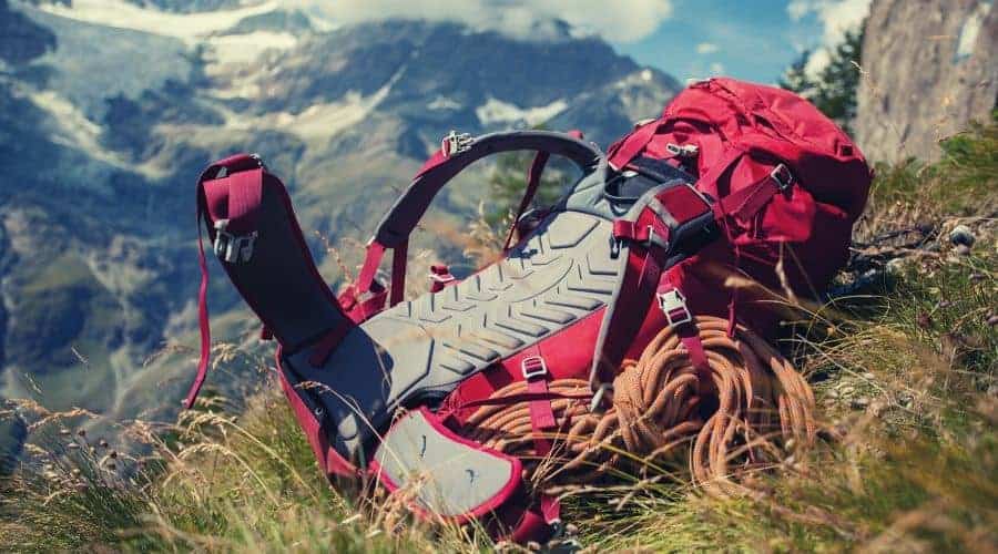 red hiking backpack lying on mountainous hillside intext