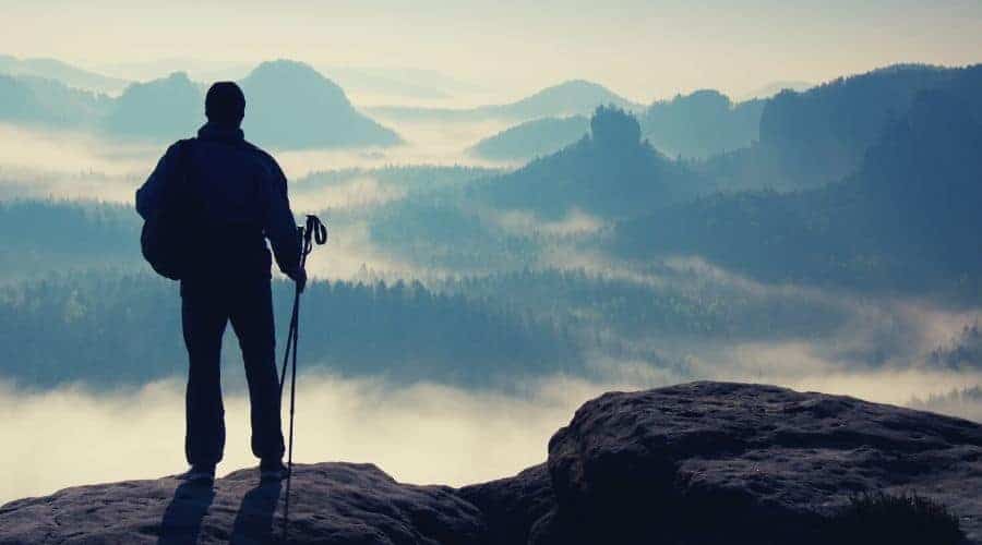 silhouette of thru hiker looking over forested valley intext