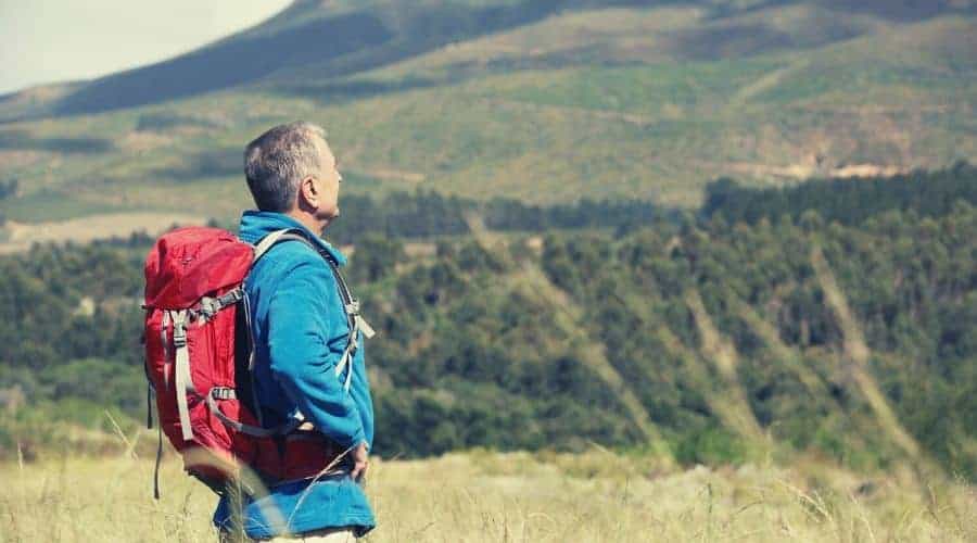 mature hiker in blue fleece admiring mountain view