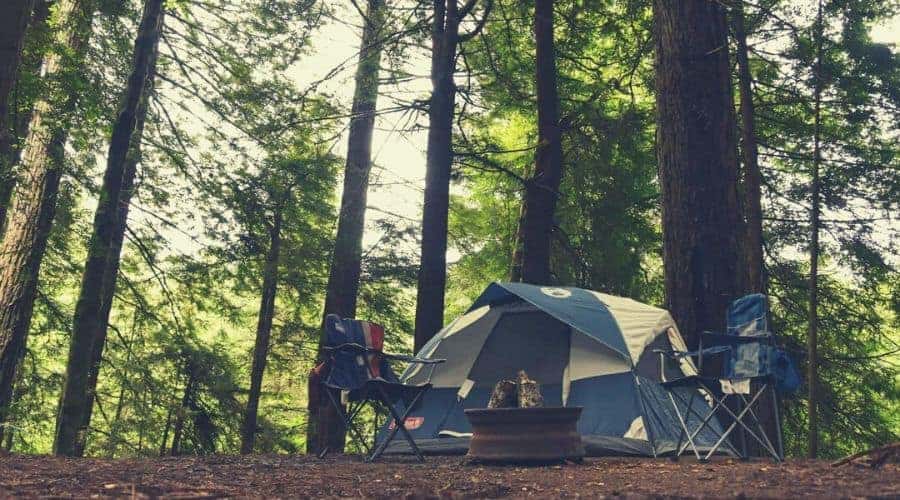 tent and two camping chairs in forest