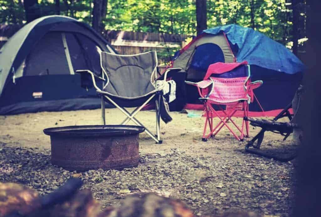 Campsite setup with tents and chairs and fire