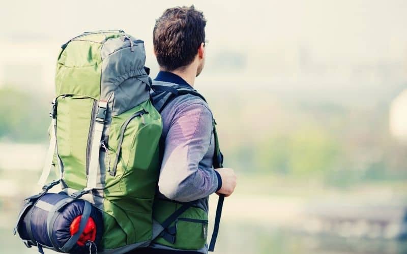 Man carrying large backpack with sleeping bag attached