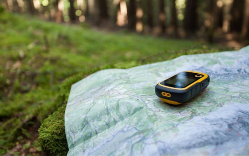 A handheld GPS device sitting on top of a map