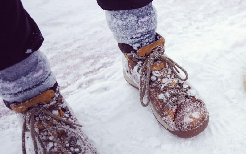 Close up of person wearing hiking boots and socks in the snow