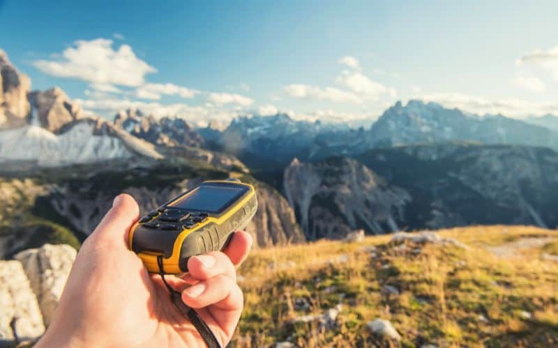 GPS device held in front of rocky mountainous terrain