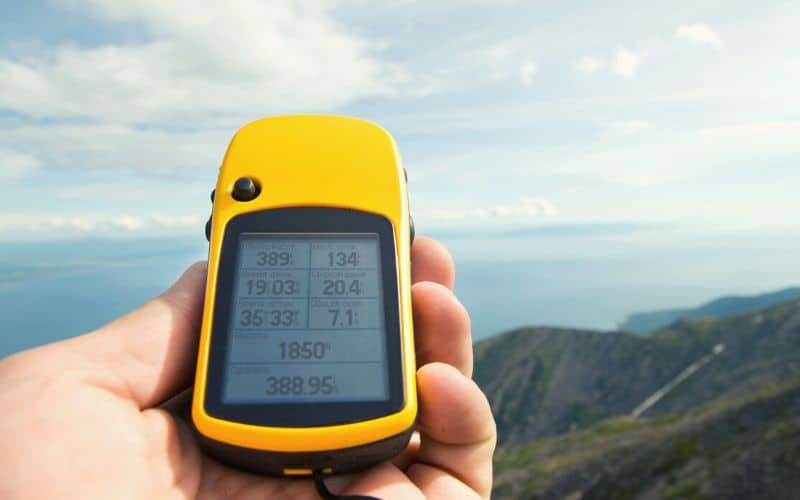 Handheld GPS device held in front of hills