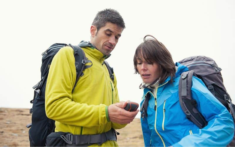 Two hikers looking at a GPS unit