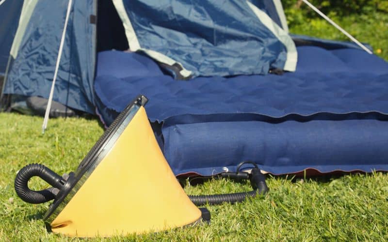 Air pump in front of a blow up mattress and tent