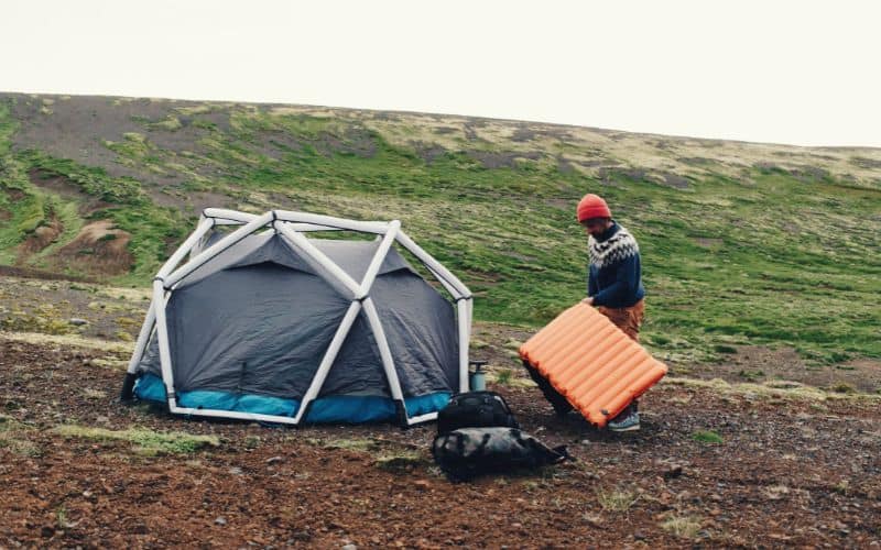 Man with inflatable mattress and inflatable tent pitched