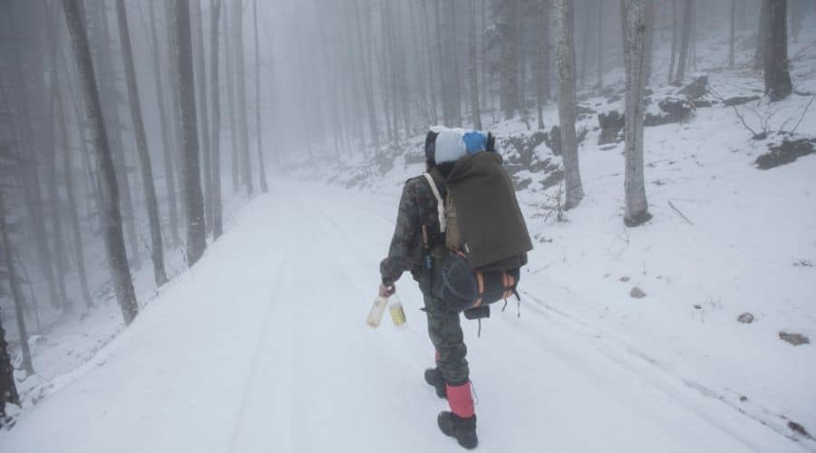 backpacker walk in snowy woods water bottles