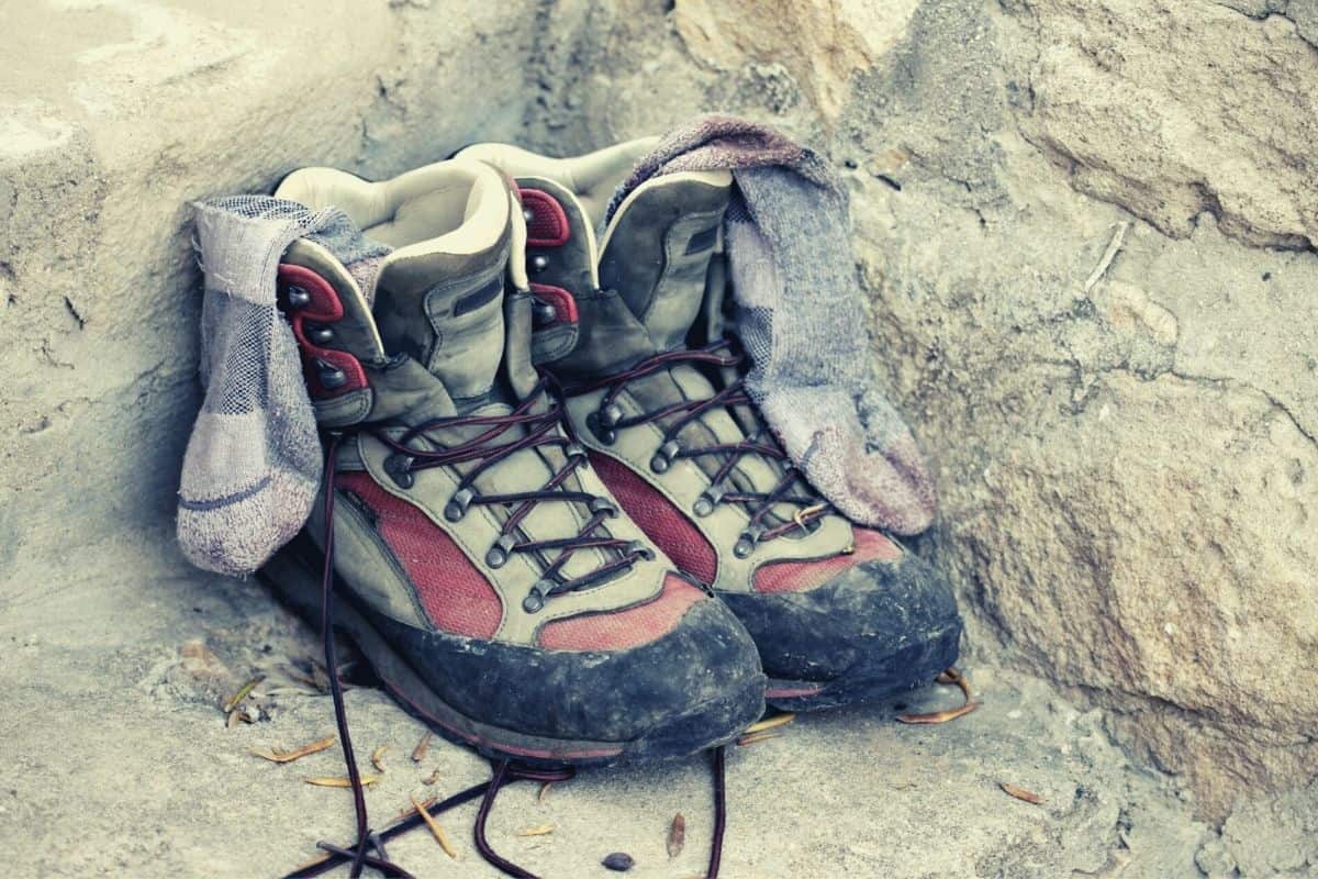 pair of hiking boots and wool socks on rock - benefits of wool socks featimg