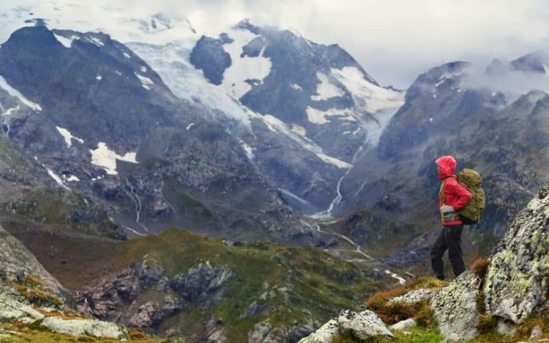 hiker in hardshell jacket overlooking mountain valley