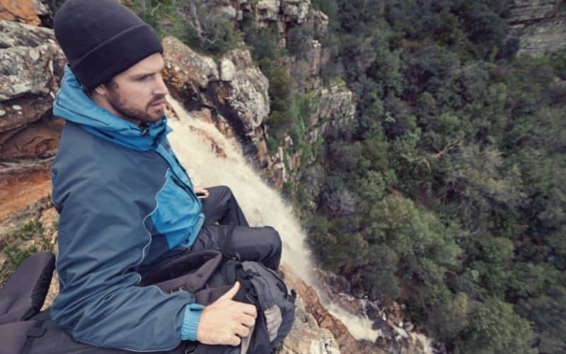 Man wearing beanis sitting at top of waterfall