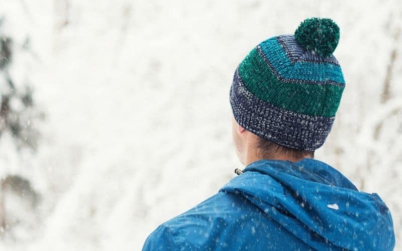 Man wearing beanie standing in the snow