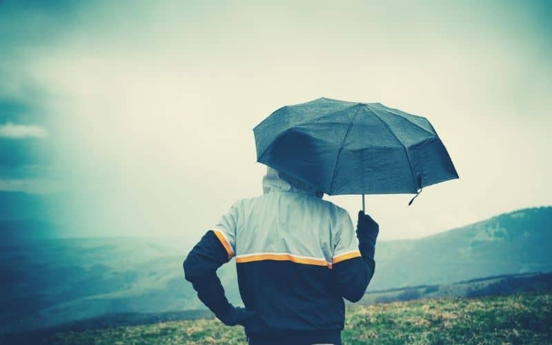 hiker on hill with umbrella