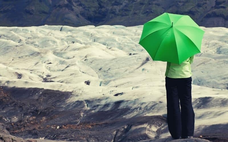 woman hiker with umbrella standing in front of glacier