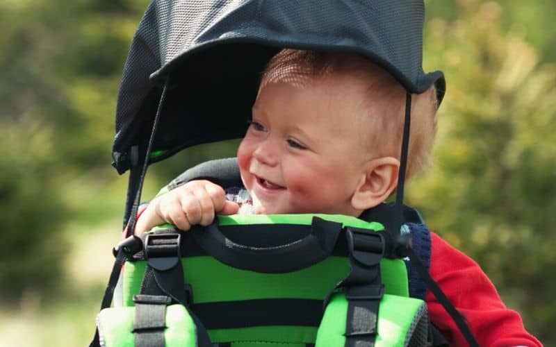 Baby in backpack carrier with a sunshade over him