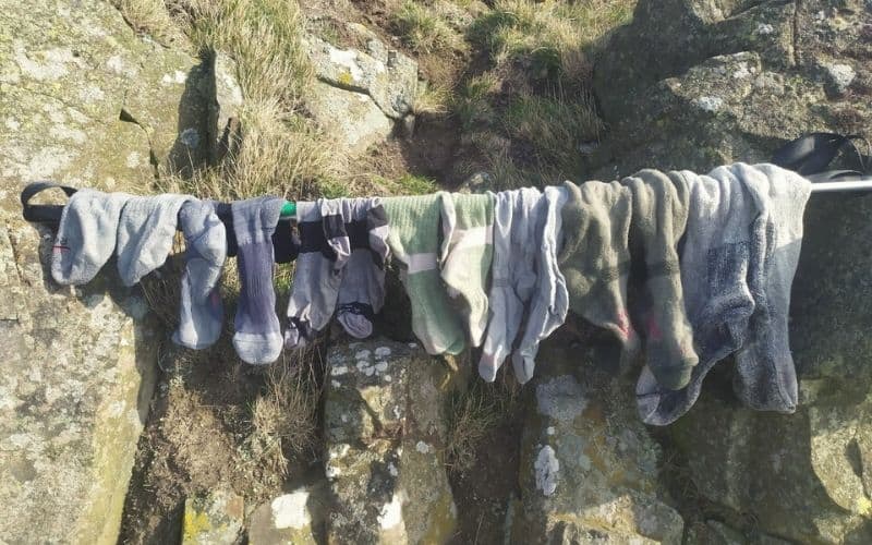 Different sizes of hiking socks drying on a makeshift washing line