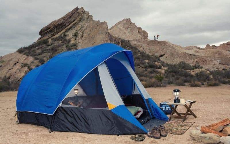 Dome tent pitched in front of rocks on a beach