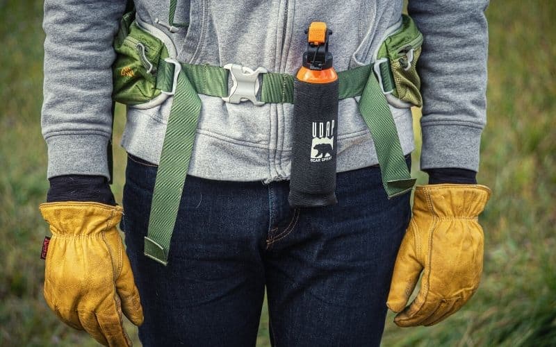Hiker carrying bear spray in a holster attached to his bags hip strap