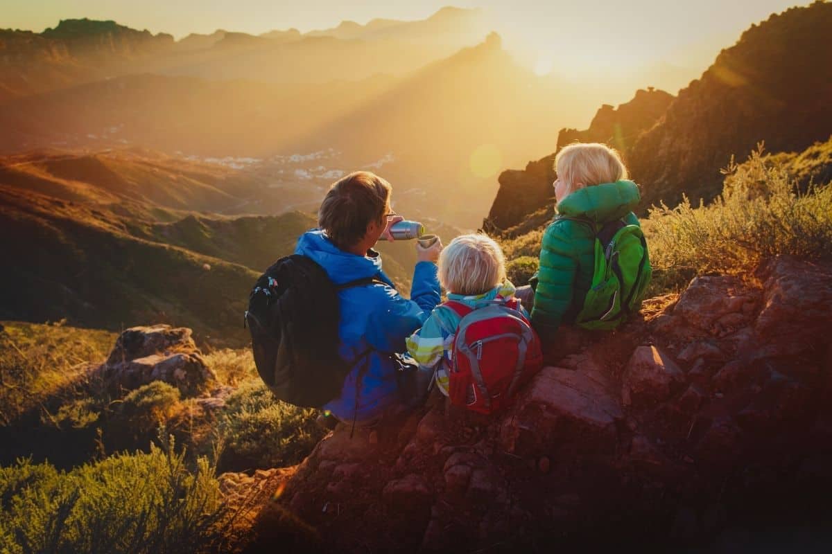Parent and kids sitting on hillside drinking tea