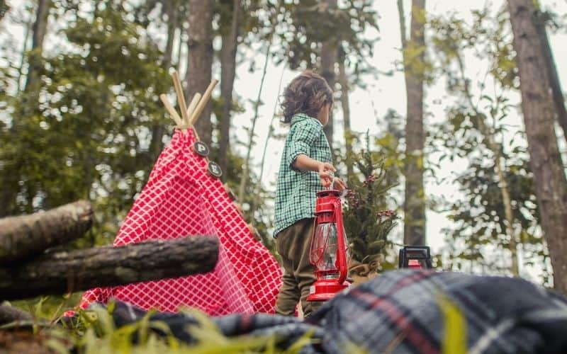 Kid playing camp with a toy teepee