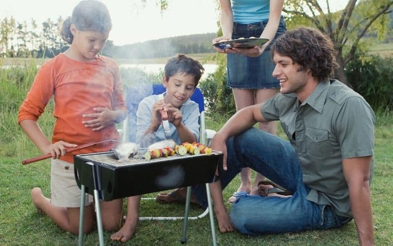 Kids cooking kebabs over a camping bbq grill