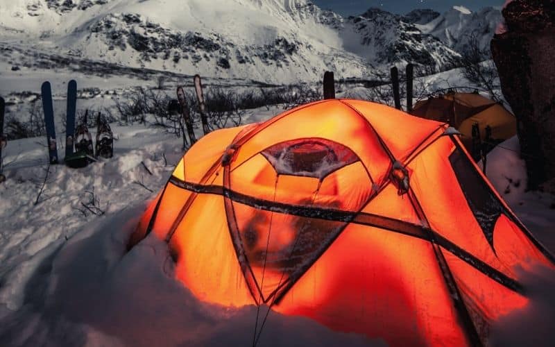 Lit up tent pitched up in the snow