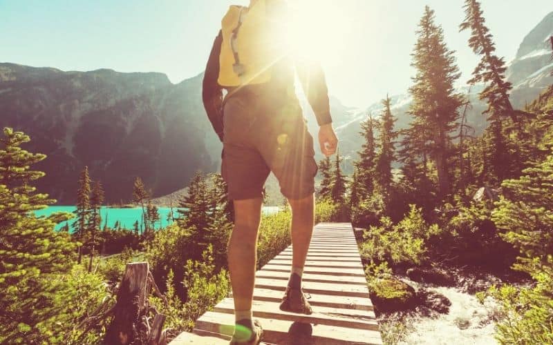 Man hiking in mountains with sun shining on him