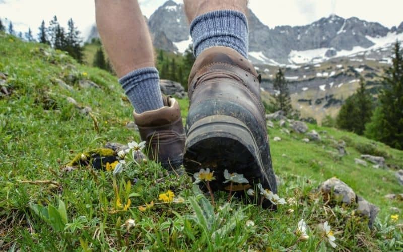 Man walking over alpine field in hiking boots and socks