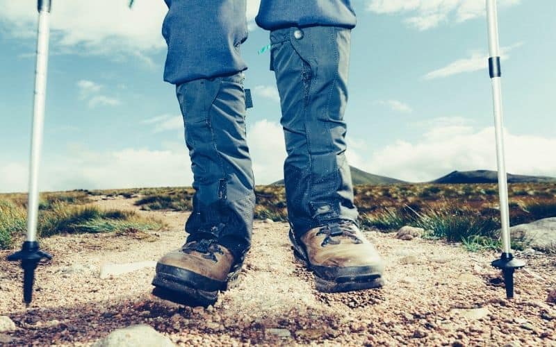 Man wearing gaiters and holding trekking poles