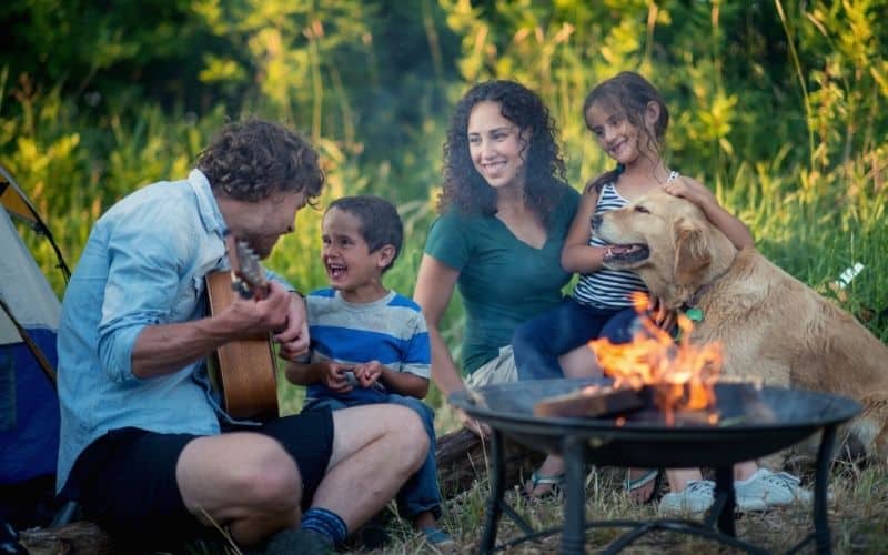 Parents and kid singing songs beside a tent