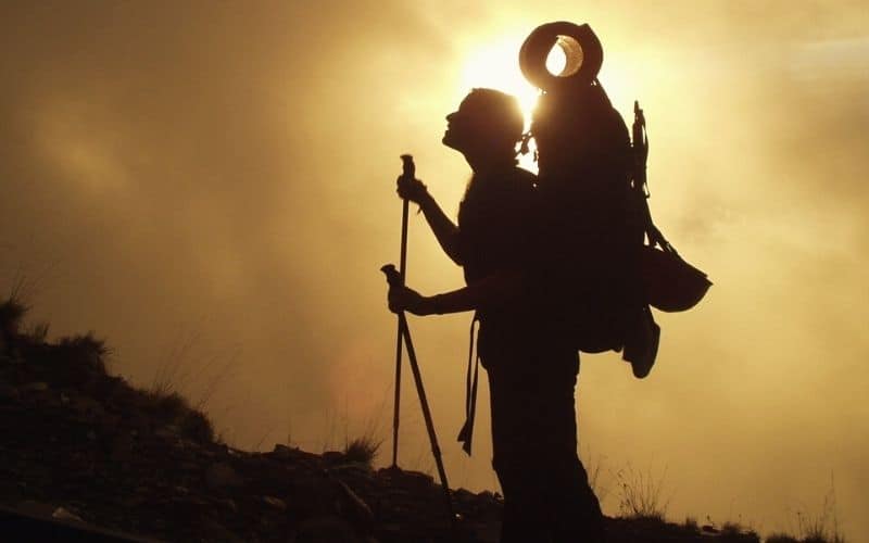 Silhouette of hiker with tall backpack on