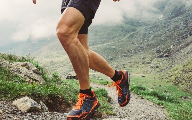 Trail runner running up mountain in ankle socks and trail running shoes