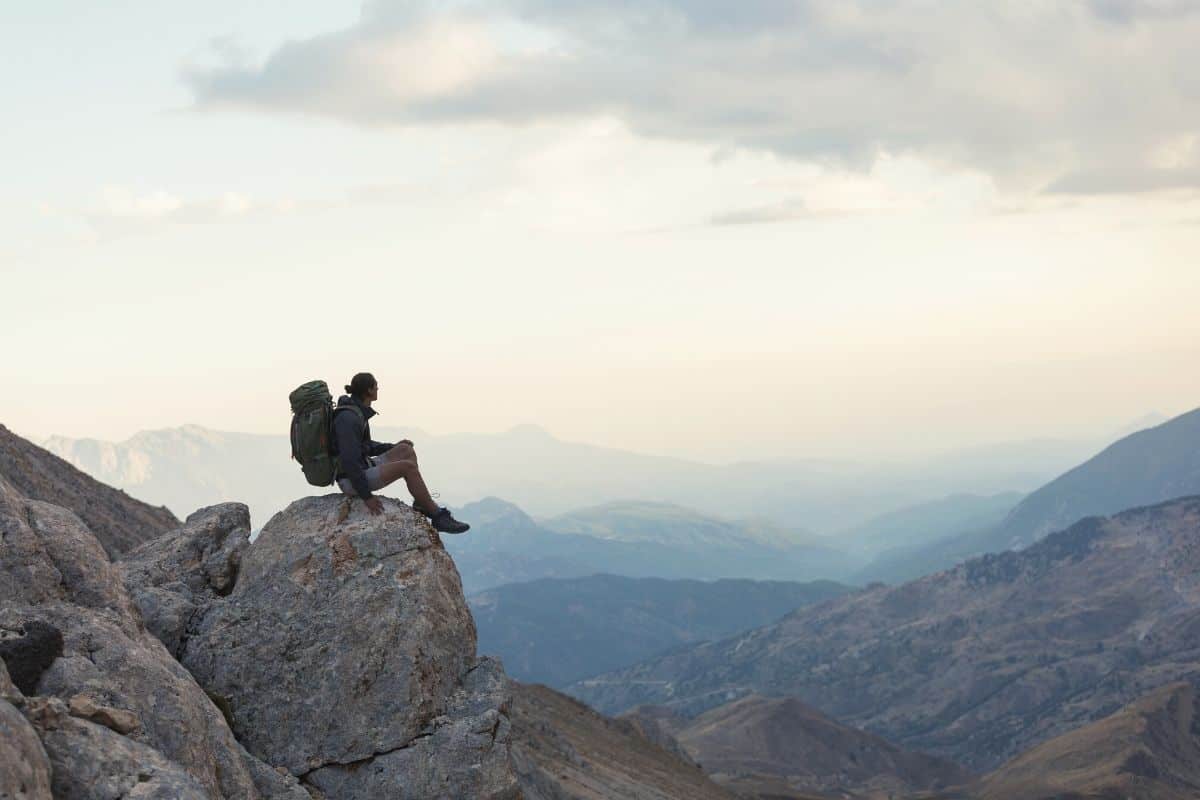 Hiker wearing backpack sitting on mountain edge