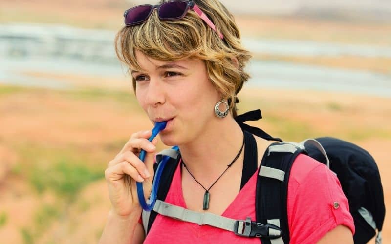 Woman drinking through tube attached to a hydration bladder
