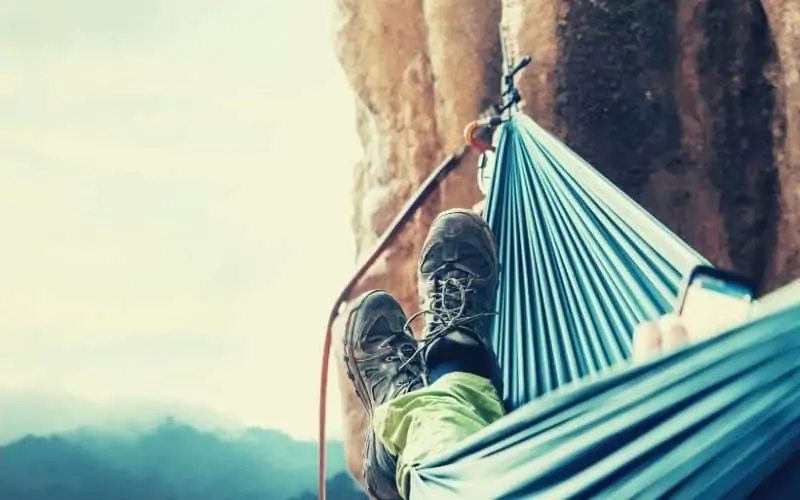 climber hanging in a hammock off a cliff face