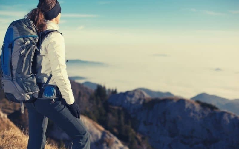 female hiker in light jacket overlooking mountains