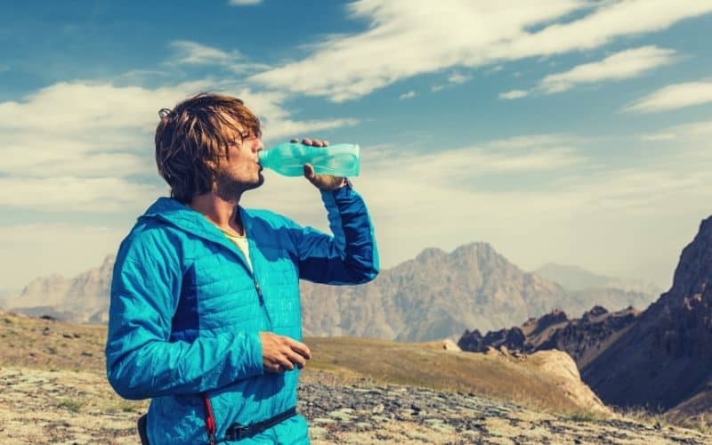 Hiker drinking water while wearing lightweight down jacket