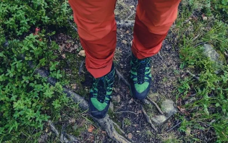 hiking wearing bright red hiking pants and green shoes